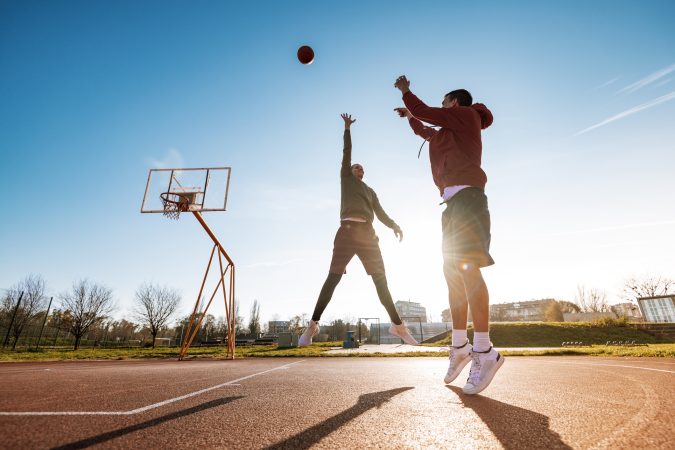 Man and woman playing basketball outdoors in winter or autumn, plenty of copy space on the image