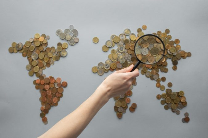 image of a map made of coins with a magnifying glass looking at China