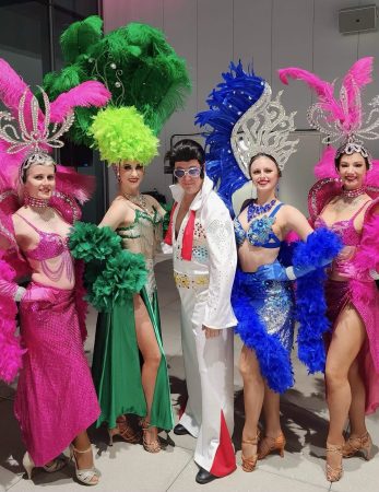 photo of Elvis impersonator and women in feathered head dresses, these are performers Baskow Talent books regularly