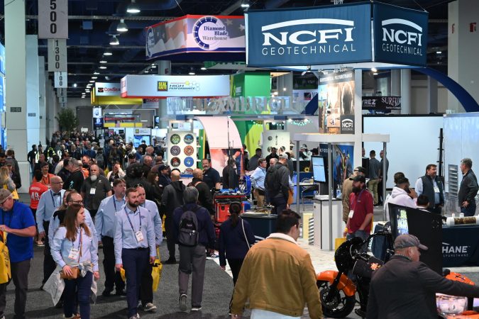 attendees of World of Concrete walking around the show floor around exhibition booths